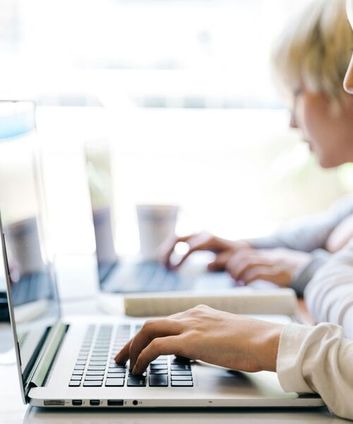 Personen arbeiten konzentriert an Laptops in heller, moderner Umgebung.