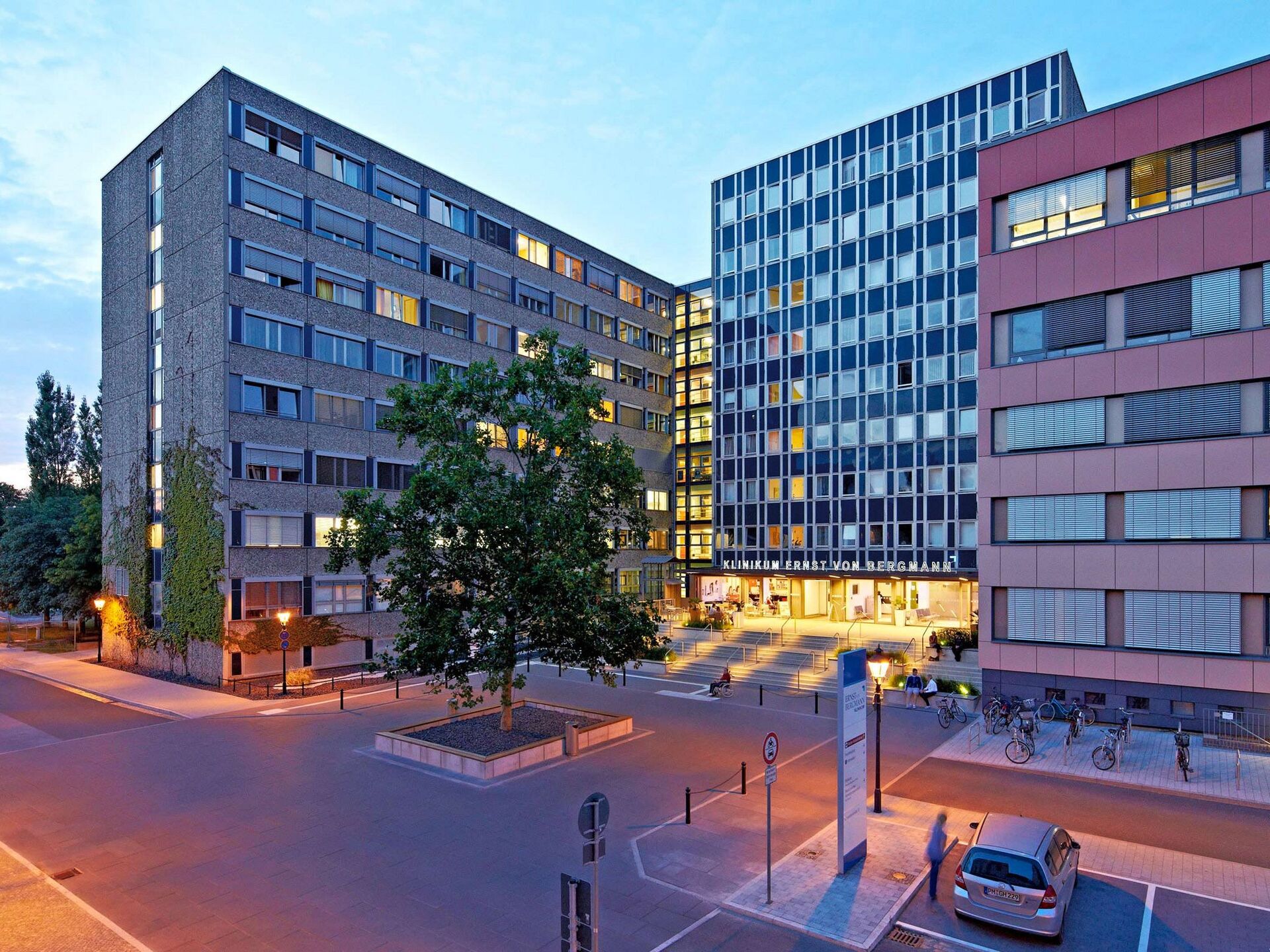 Beleuchteter Eingangsbereich eines modernen Klinikgebäudes am Abend.