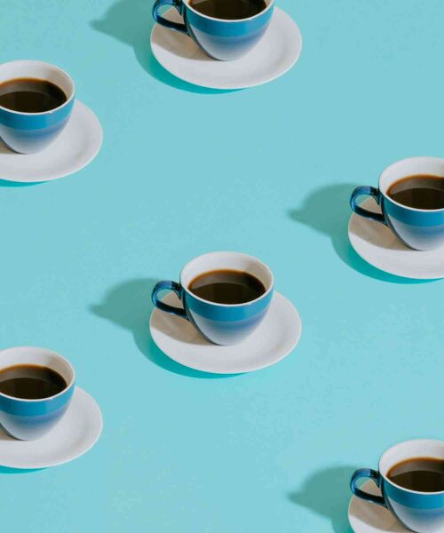 Mehrfach angeordnete Kaffeetassen auf hellem, mintfarbenem Hintergrund.